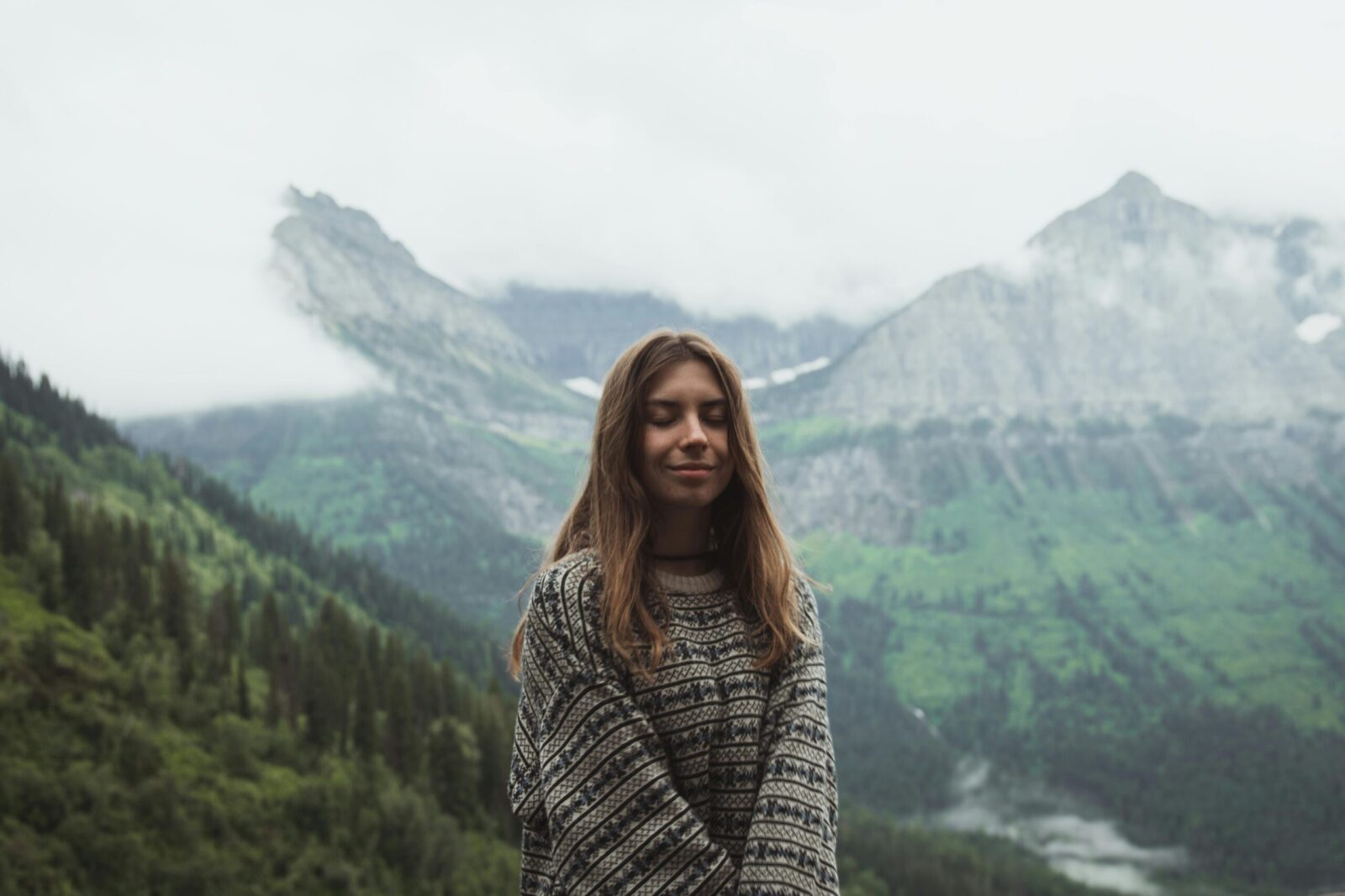Woman enjoying a serene moment in Montana mountains with misty backdrop.